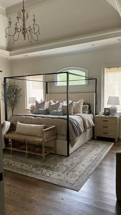 a bedroom with a four poster bed and chandelier