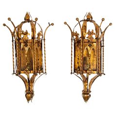 two golden metal sconces with carvings on them