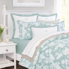 a bed with blue and white comforters in a bedroom next to a table with flowers on it