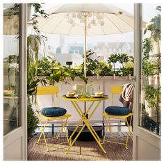 a table with two chairs and an umbrella on top of it in front of some plants