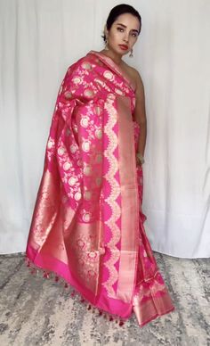 This stunning pink 100% Mulberry Katan silk saree is handwoven in Banaras, known for its intricate designs and high-quality craftsmanship. The saree features a beautiful shade of dual pink with gold and silver zari jaal work creating a mesmerizing effect. Loolong for a distinct saree - this is the one with silver zari outlining . The saree is perfect for any special occasion, such as a wedding, festival, or formal event. Comes finished with hand fall and Pico. And a blouse piece with zari border. Silk Mark Certified Note: Colors that show up on your screen may vary slightly from the actual product due to variations in settings. Also, the actual product may appear to be different hues depending on the ambience lighting.Note: There may be very slight inconsistencies such as in the weave/moti Saree Blouse, Blouse Piece, Blouse Dress, Formal Event, Silk Sarees, Hand Weaving, Saree, Silk, Festival