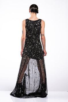 a woman in a long black dress with stars on the back and sheer mesh overlays