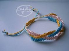 three bracelets with different colors and sizes on a white surface, one has a blue string