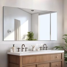 a bathroom vanity with two sinks and a large mirror above it, next to a potted plant