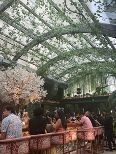 people sitting at tables in a restaurant under a glass roof