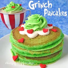 a stack of green pancakes on a white plate next to a red and white striped cup