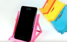 a cell phone sitting on top of a pink and blue holder next to colorful chairs