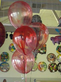 several balloons are floating in the air near plates and magnets on the wall behind them