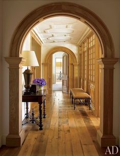 an archway leads into a hallway with wood flooring and wooden furniture on either side