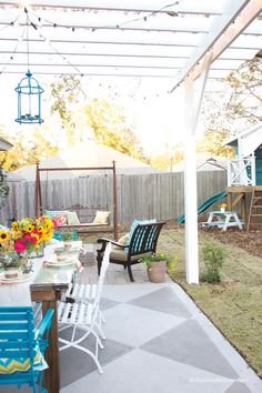 an outdoor dining area with blue chairs and sunflowers in vases on the table