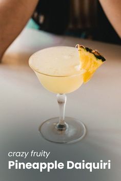 a close up of a drink in a glass with a pineapple garnish on the rim