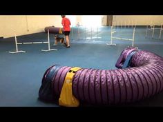 a man standing next to an inflatable purple tube on the ground with ropes around it