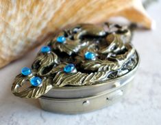 a close up of a metal container with blue beads on it and a shell in the background