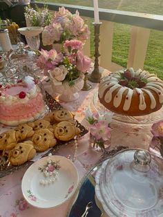 a table topped with cakes and desserts on top of a pink cloth covered table