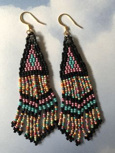 Stunning long metallic handmade seed earrings made with matte black square beads with pink, turquoise and soft matte pastel multicolored 11/0 seed beads. The earrings have long flowing fringe. The french hook earwires and findings are14kt gold plated. These gorgeous Cheyenne style earrings are super long and brush your shoulders ever so slightly. Great for daywear and stunningly beautiful for the night out. Earrings measure approximately 3-1/2 inches including ear wires. All items are handmade a Bohemian Long Drop Earrings With Dangling Beads, Black Dangling Beads Jewelry For Beach, Beach Jewelry With Black Dangling Beads, Handmade Teardrop Bohemian Beads, Bohemian Long Drop Beaded Earrings, Black Beach Jewelry With Dangling Beads, Multicolor Long Drop Tassel Earrings With Dangling Beads, Bohemian Teardrop Beaded Earrings With Colorful Beads, Bohemian Long Drop Earrings With Colorful Beads