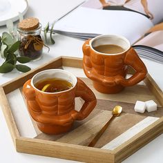 two mugs of tea sit on a tray