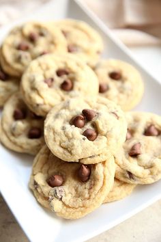 chocolate chip cookies stacked on top of each other in a square white plate, ready to be eaten