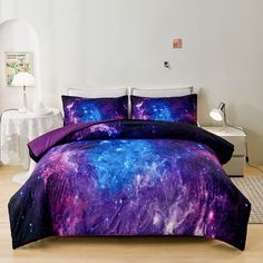 a bed covered in purple and blue galaxy comforter