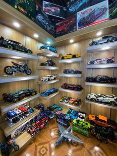 a room filled with lots of toy cars on shelves next to wall mounted tvs