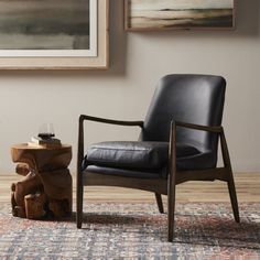 a black leather chair sitting on top of a wooden table next to a tree stump