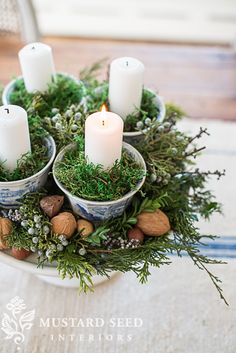 candles are placed in small bowls filled with greenery and nuts