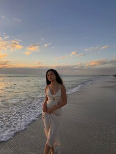 a woman standing on top of a beach next to the ocean