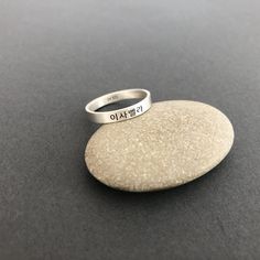 This listing is for a personalized burnished matte sterling silver engraved Korean Name ring. The sample ring is engraved with a name Isabella in Korean in the font #1. Please check the font options in the pictures. Outside or/and inside of the ring can be engraved. The sample ring is about 3 mm wide. All orders come gift-wrapped. Avoid dust, moisture and direct light to ensure the jewelry does not tarnish and discolor. << How to order >> Please choose engravings sides and a ring siz Promise Sterling Silver Engraved Ring, Promise Sterling Silver Ring With Engraved Text, Meaningful Engraved Silver Rings, Customizable Sterling Silver Promise Ring, Minimalist Sterling Silver Jewelry With Engraved Text, Sterling Silver Promise Ring With Engraved Text, Symbolic Engraved Stackable Rings For Anniversary, Silver Engraved Ring With Stamped Detail For Promise, Symbolic Engraved Stamped Ring For Promise