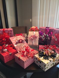 several presents are stacked on top of each other in pink and red boxes with bows