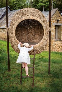 a woman standing on a ladder holding up a large piece of straw in front of her face