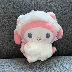 a hello kitty stuffed animal sitting on top of a gray couch next to a wall