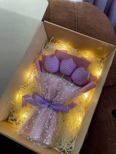 a box filled with purple crocheted flowers and lights