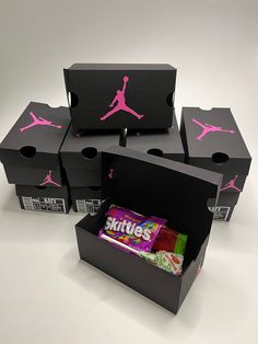 four black boxes with pink jordans on them and candy in the bottom one box