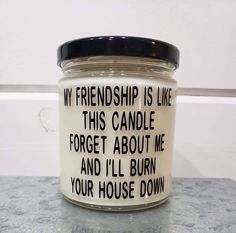 a white candle with black writing on it sitting on top of a gray countertop