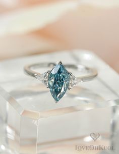 a blue diamond ring sitting on top of a clear box