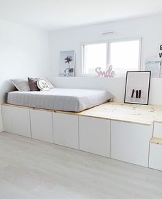 a bed sitting on top of a wooden platform in a bedroom next to a window