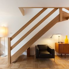 a chair and lamp in a room with white walls, wood floors and wooden beams