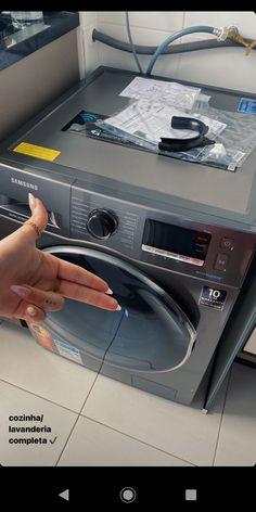 a woman's hand is pointing at the front of a washing machine