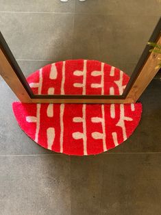 a red and white rug on the floor in front of a door with an open handle