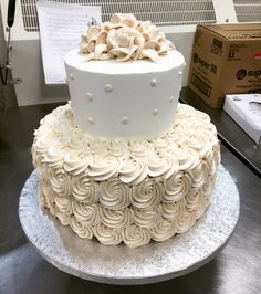 a three tiered cake with white frosting roses