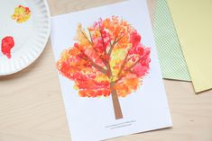 a paper plate with an autumn tree on it next to a crafting activity book