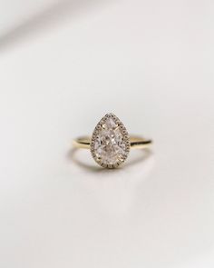 an oval shaped diamond ring on a white surface