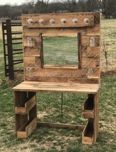 a wooden vanity with mirror and drawers in the middle of a grassy field next to a fence