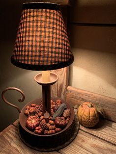 a lamp that is sitting on top of a table next to some pumpkins and nuts