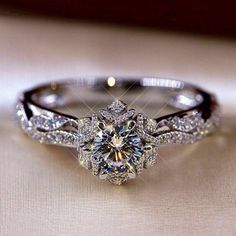 an engagement ring with diamonds on it sitting on top of a white cloth covered table