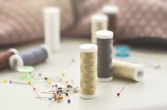 several spools of thread sitting on top of a table next to sewing needles