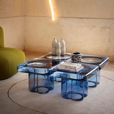 a table with two vases on top of it in front of a green chair