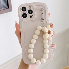 a person holding up a cell phone case with white beads on the front and sides