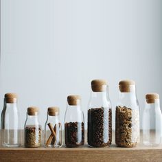 five glass bottles with different types of spices in them on a table top next to each other