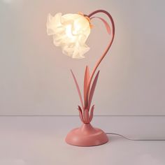 a pink table lamp with a white flower on it's base and a light bulb in the shape of a heart