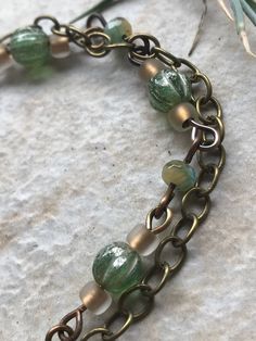 This bracelet was made by me in my studio, including the ceramic focal bead. It is glazed on both sides, though it definitely has a "front" and "back," as it is curved to fit the wrist. The wire and clasp are antique brass. This bracelet has a stacked or layered look, with multiple strands. The bracelet is 9 inches long and is adjustable to 7.75 inches. It weighs 18 grams. An average fork weighs 35 grams, and a Sharpie marker weighs 9 grams if you need a reference. All items are one of a kind - Brass Beaded Bracelets With Round Beads, Handmade Spiritual Brass Beaded Bracelets, Handmade Copper Beaded Bracelets With Round Beads, Handmade Copper Beaded Bracelets, Handmade Bronze Jewelry With Czech Glass, Handmade Czech Glass Bronze Jewelry, Handmade Brass Round Beaded Bracelets, Handmade Brass Bracelets With Round Beads, Handmade Green Brass Bracelets